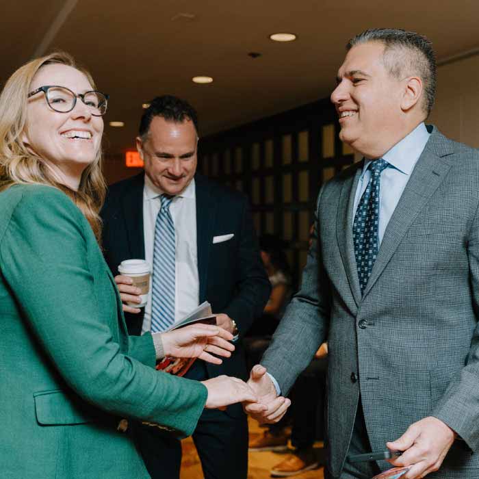 Two agents shaking hands at a networking event